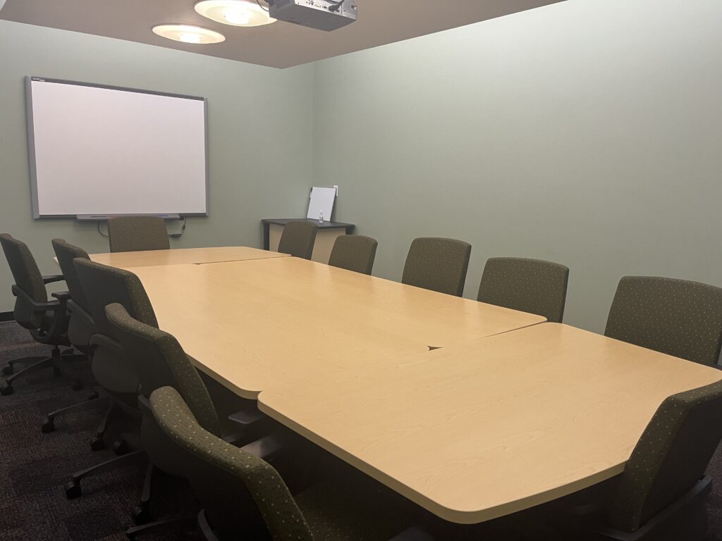 Compact meeting room containing a long table and a projector